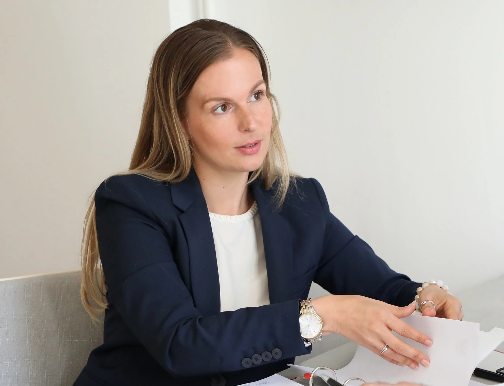 Junge Geschäftsfrau im Gespräch beim Meeting, hält Unterlagen am Schreibtisch.